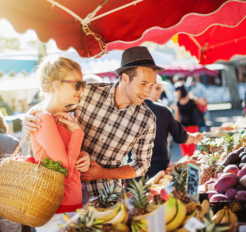 a young couple buying fruits and vegetables at a farmers market